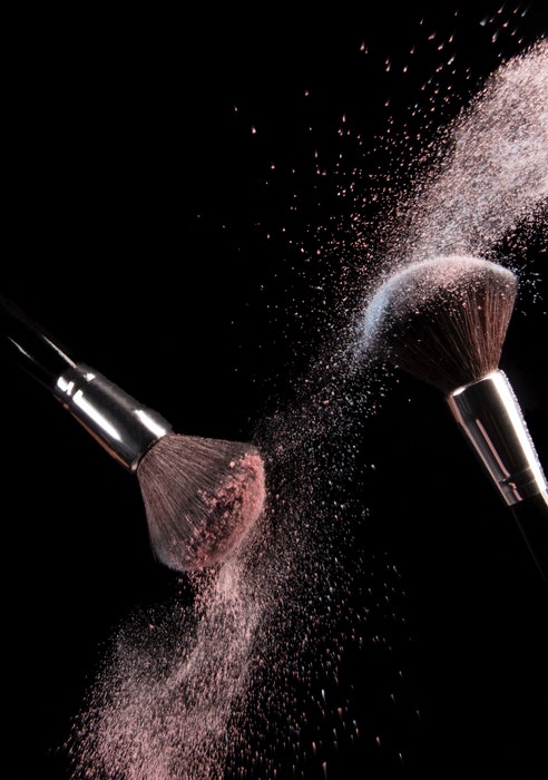 Make up brushes with powder flying from them 