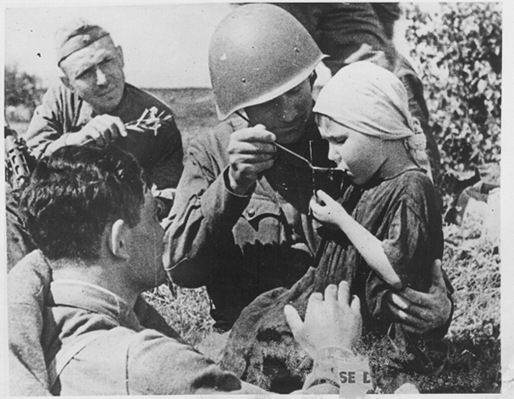 Бойцы Красной армии кормят маленькую девочку.