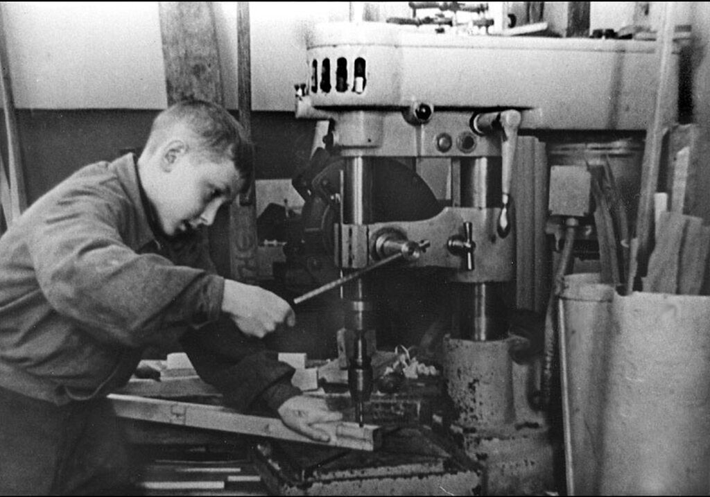 Подросток, работающий на сверлильном станке на оборонном заводе.