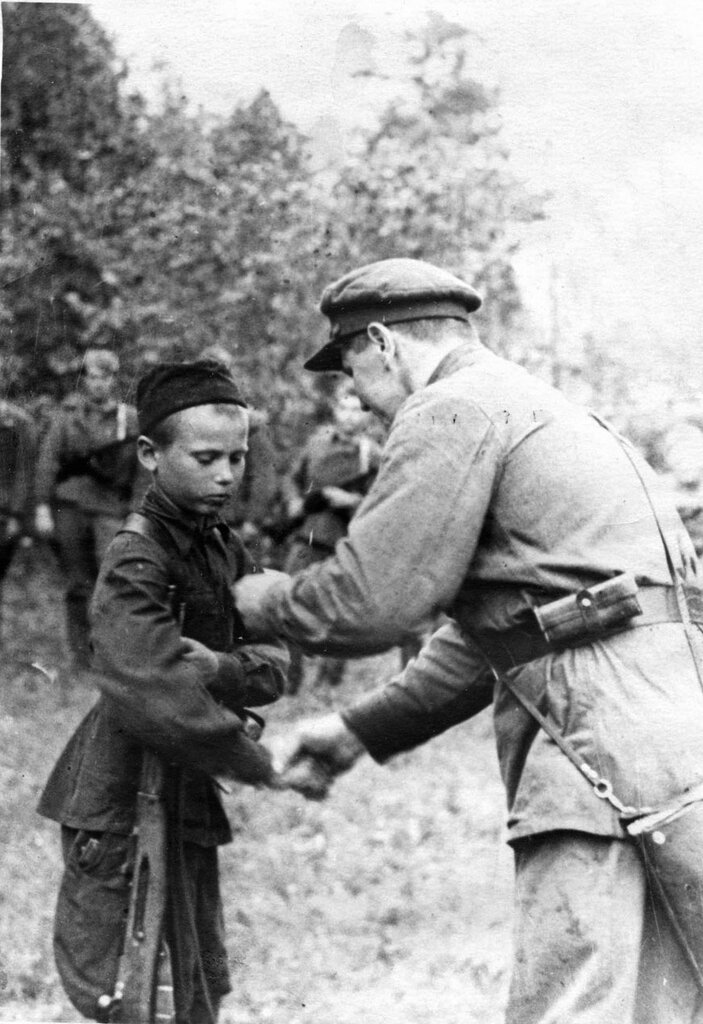 Командир партизанского отряда вручает медаль «За отвагу» юному партизану-разведчику. 1942 г.